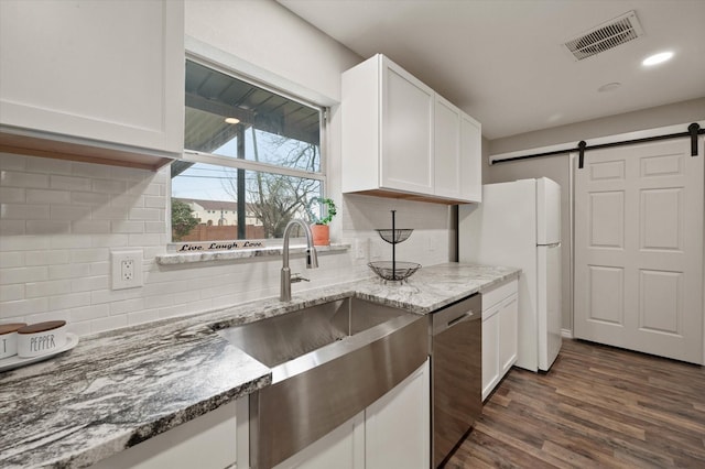 14053 Stardust Ln, Farmers Branch, TX 75234 - kitchen featuring stainless steel dishwasher, a barn door, a sink, freestanding refrigerator, and white cabinetry