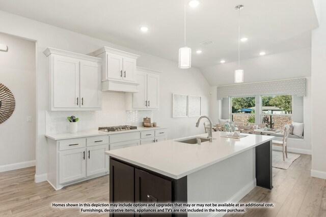 12709 Cactus Ct, Godley, TX 76044 - kitchen featuring a sink, stainless steel gas cooktop, decorative backsplash, light wood-style flooring, and white cabinetry