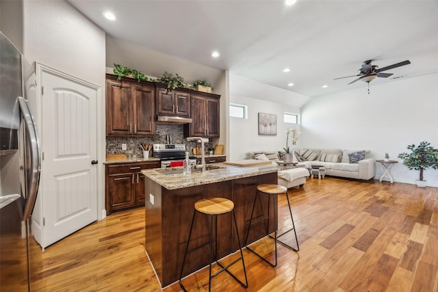 2405 La Costa Dr, Rowlett, TX 75088 - kitchen featuring stainless steel appliances, under cabinet range hood, light wood-style floors, a sink, and a kitchen breakfast bar