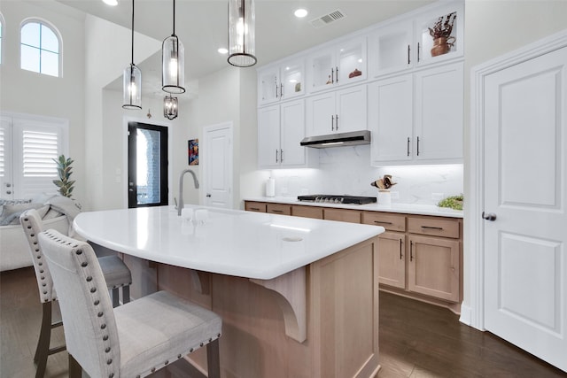 3736 Queen Rd, Sherman, TX 75090 - kitchen featuring under cabinet range hood, stainless steel gas stovetop, a breakfast bar area, glass insert cabinets, and tasteful backsplash