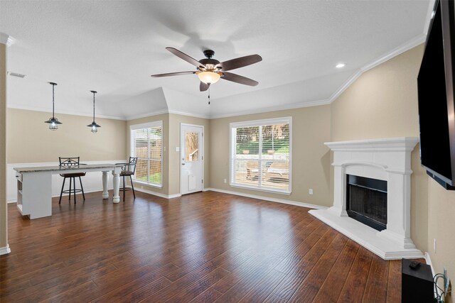 235 Carriage Dr, Willow Park, TX 76087 - living area featuring a ceiling fan, dark wood-style floors, a fireplace with raised hearth, baseboards, and crown molding