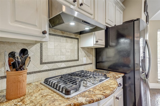 3401 Beckingham Ct, Flower Mound, TX 75022 - kitchen featuring under cabinet range hood, appliances with stainless steel finishes, white cabinetry, tasteful backsplash, and light stone counters