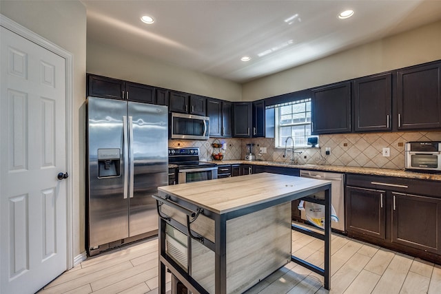 2446 Catherine St, Dallas, TX 75211 - kitchen featuring appliances with stainless steel finishes, a sink, decorative backsplash, wood tiled floors, and recessed lighting