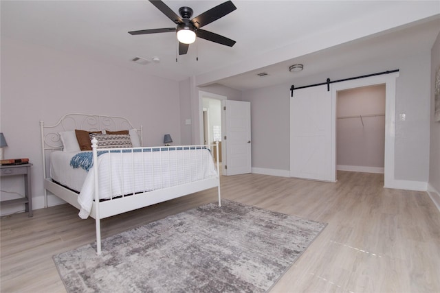916 Wilde St, Denison, TX 75020 - bedroom with a barn door, wood finished floors, baseboards, and ceiling fan