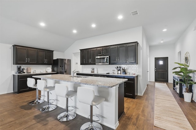1417 Grassy Meadows Dr, Burleson, TX 76058 - kitchen featuring appliances with stainless steel finishes, a sink, a center island with sink, tasteful backsplash, and a kitchen bar