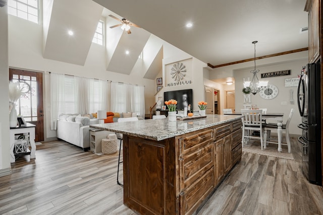 3547 County Road 1092, Celeste, TX 75423 - kitchen with freestanding refrigerator, a kitchen breakfast bar, a ceiling fan, open floor plan, and wood finished floors