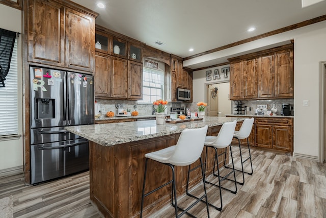 3547 County Road 1092, Celeste, TX 75423 - kitchen featuring appliances with stainless steel finishes, light wood-type flooring, tasteful backsplash, a center island, and a kitchen bar