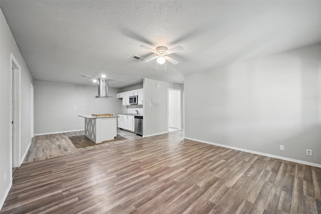 1043 Star St, Denison, TX 75020 - unfurnished living room with wood finished floors, baseboards, and a textured ceiling