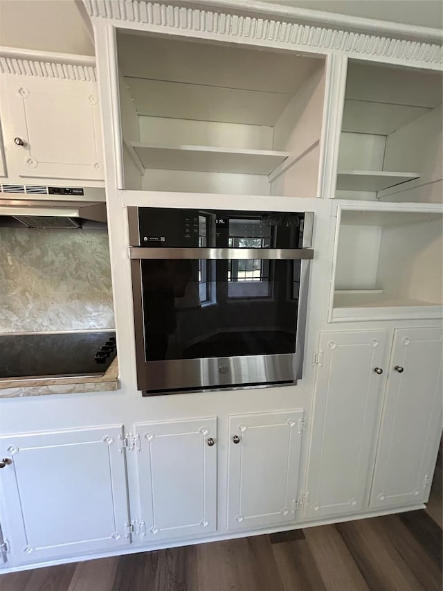 3026 San Miguel Dr, Abilene, TX 79605 - kitchen view of under cabinet range hood, black electric stovetop, stainless steel oven, and dark wood-style flooring