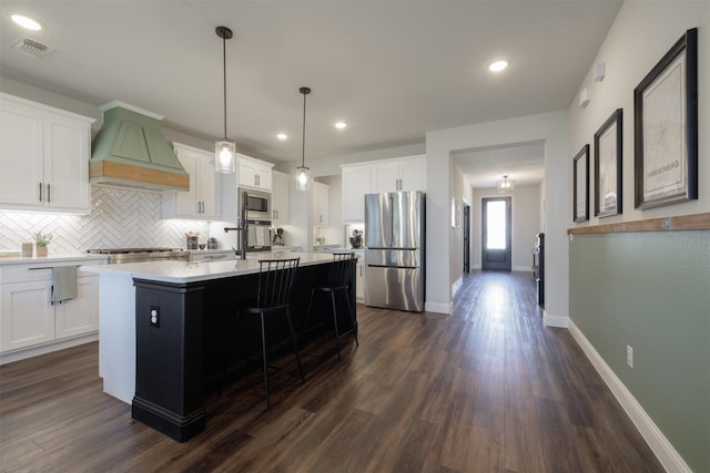 664 Fletcher Dr, Fate, TX 75087 - kitchen with appliances with stainless steel finishes, premium range hood, dark wood-type flooring, tasteful backsplash, and light countertops