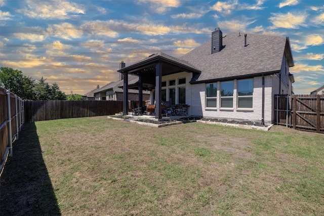 664 Fletcher Dr, Fate, TX 75087 - back of house at dusk featuring brick siding, a patio area, a shingled roof, and a chimney