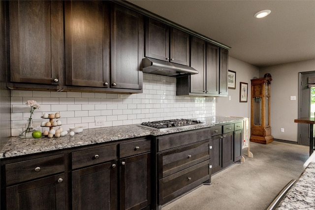 14447 Warbler Ln, Haslet, TX 76052 - kitchen with stainless steel gas cooktop, under cabinet range hood, dark brown cabinets, tasteful backsplash, and light stone countertops