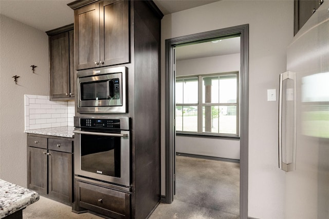 14447 Warbler Ln, Haslet, TX 76052 - kitchen featuring appliances with stainless steel finishes, dark brown cabinetry, backsplash, and light stone counters