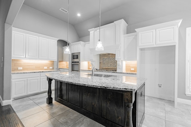 913 Colby Bluff Dr, Rockwall, TX 75087 - kitchen featuring stainless steel appliances, a center island with sink, white cabinets, backsplash, and vaulted ceiling