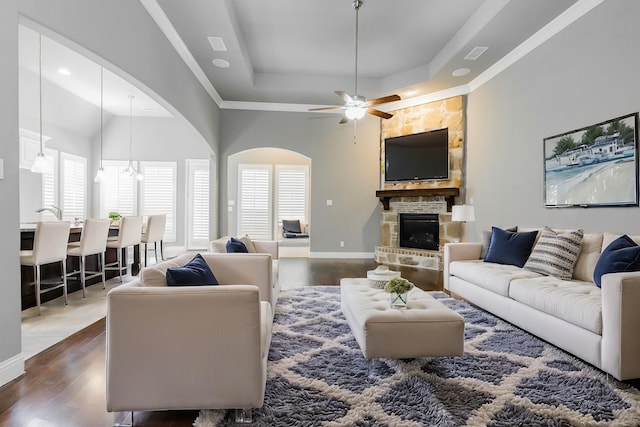 913 Colby Bluff Dr, Rockwall, TX 75087 - living room with a raised ceiling, wood finished floors, a stone fireplace, a high ceiling, and ceiling fan