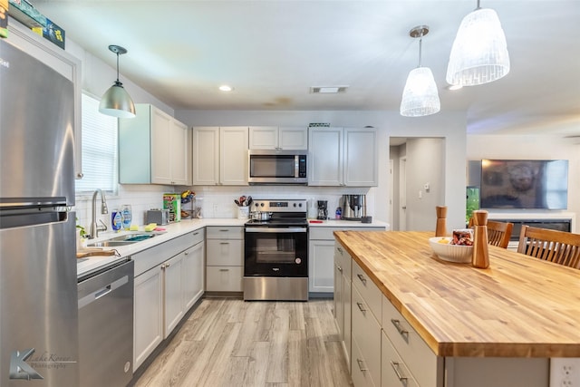 601 Westmoreland St, Abilene, TX 79603 - kitchen with wood counters, stainless steel appliances, light wood-type flooring, tasteful backsplash, and a sink