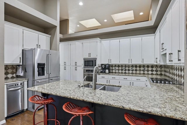 450 Craig Cir, Highland Village, TX 75077 - kitchen featuring a sink, appliances with stainless steel finishes, a skylight, a peninsula, and backsplash