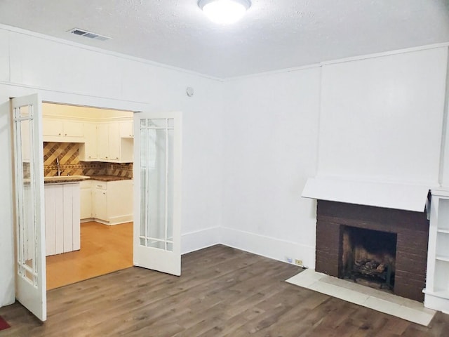 421 Jackson St, Krum, TX 76249 - unfurnished living room with wood finished floors and a brick fireplace