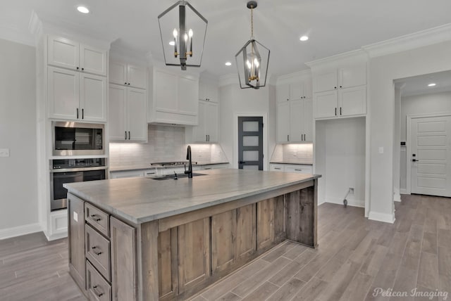 507 Cocodrie Dr, Bossier City, LA 71112 - kitchen with oven, a sink, built in microwave, a center island with sink, and baseboards