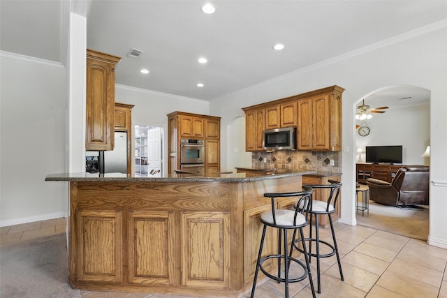 104 E Hidden Meadow Ct, Cresson, TX 76035 - kitchen featuring appliances with stainless steel finishes, arched walkways, ceiling fan, a breakfast bar, and light tile patterned flooring
