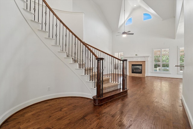 1127 Westminster Ave, Murphy, TX 75094 - stairway featuring wood finished floors, a tiled fireplace, ceiling fan, high vaulted ceiling, and baseboards