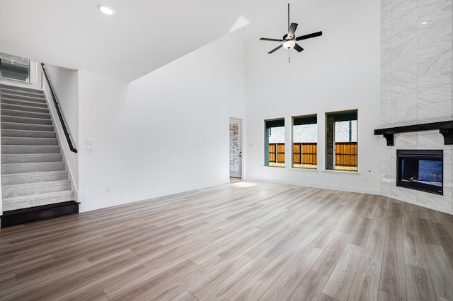 4251 Arlington Ave, Mckinney, TX 75071 - unfurnished living room with a towering ceiling, stairway, wood finished floors, a tiled fireplace, and a ceiling fan