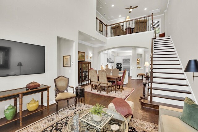 4721 Bayview Dr, Plano, TX 75093 - living area with arched walkways, a towering ceiling, crown molding, wood finished floors, and stairs