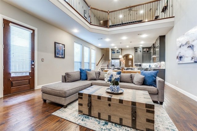 5913 Lewis St, Dallas, TX 75206 - living room featuring stairway, a high ceiling, baseboards, dark wood-style floors, and arched walkways