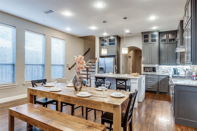 5913 Lewis St, Dallas, TX 75206 - dining room featuring arched walkways, dark wood-style floors, recessed lighting, baseboards, and stairs