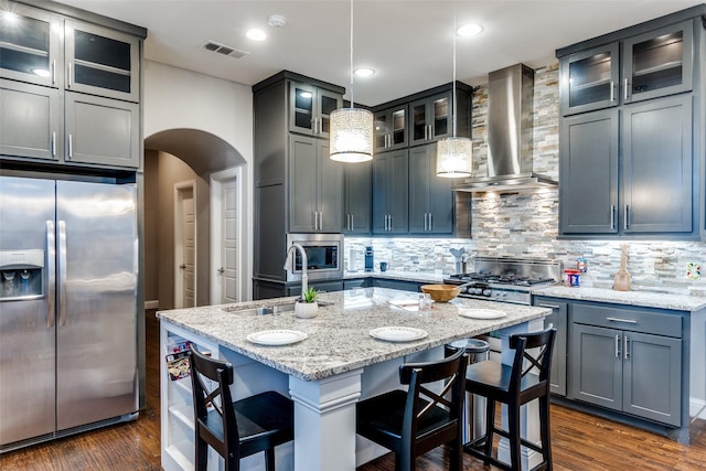 5913 Lewis St, Dallas, TX 75206 - kitchen with stainless steel appliances, wall chimney range hood, a sink, arched walkways, and backsplash