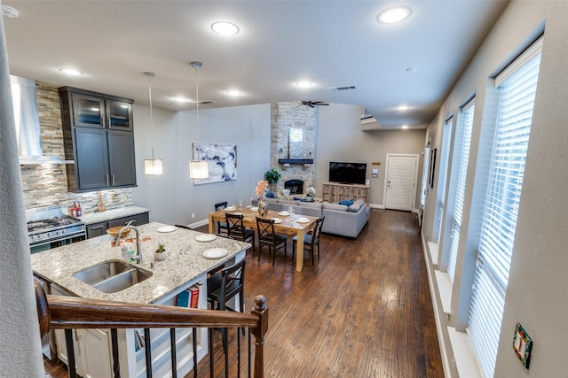 5913 Lewis St, Dallas, TX 75206 - kitchen with a sink, stainless steel gas stove, backsplash, a fireplace, and light stone countertops