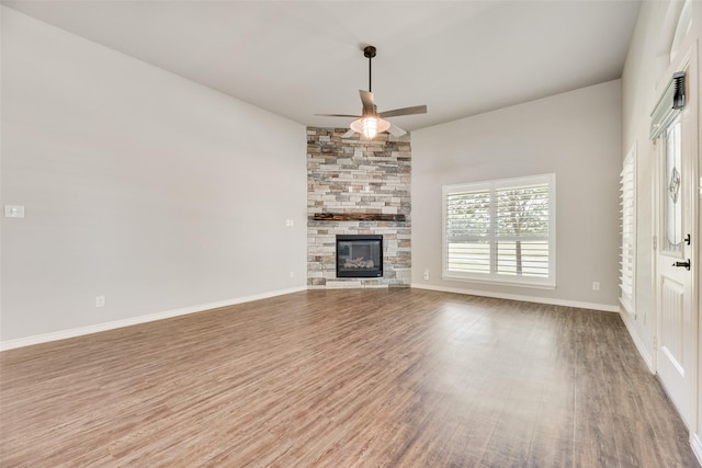 760 E Northside Dr, Pilot Point, TX 76258 - unfurnished living room with a ceiling fan, wood finished floors, a stone fireplace, and baseboards