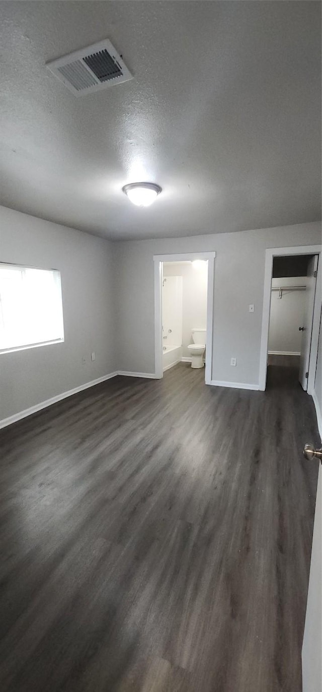 1806 Maryland Ave, Dallas, TX 75216 - unfurnished bedroom featuring dark wood-style flooring, baseboards, a textured ceiling, and ensuite bathroom