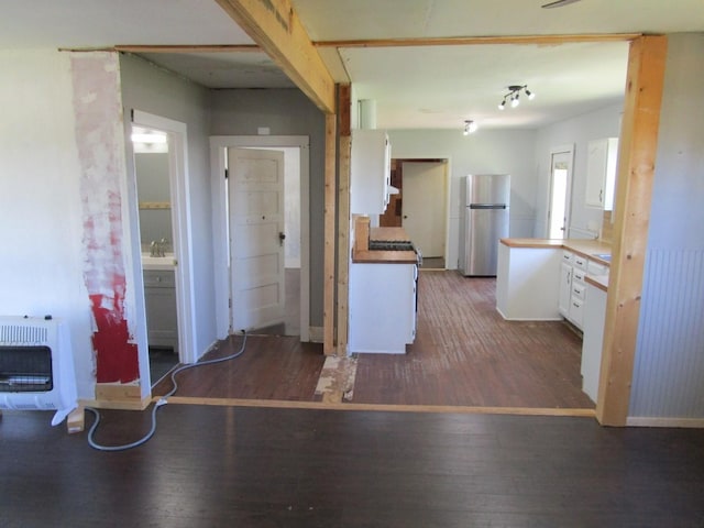 841 S 5th Ave, Munday, TX 76371 - kitchen with freestanding refrigerator, heating unit, white cabinetry, and wood finished floors