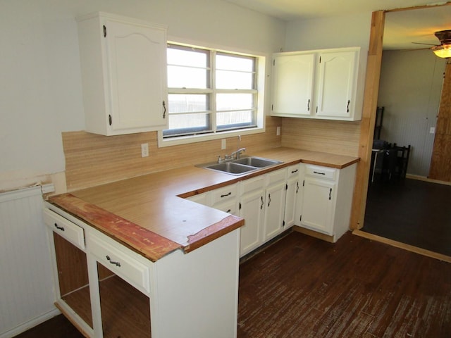 841 S 5th Ave, Munday, TX 76371 - kitchen featuring a sink, backsplash, white cabinets, and dark wood-style flooring