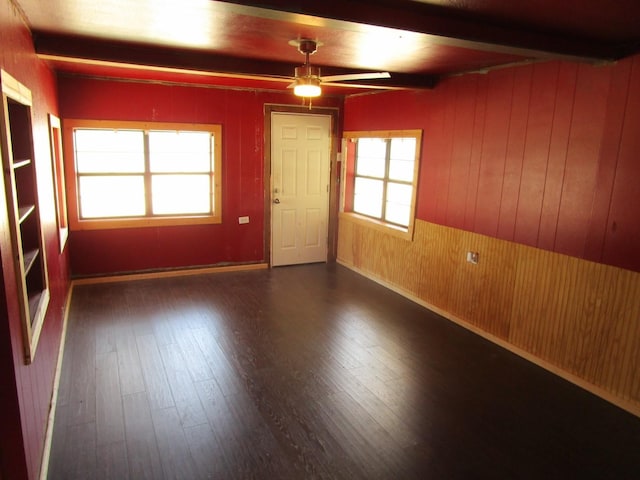 841 S 5th Ave, Munday, TX 76371 - empty room featuring ceiling fan, wood walls, beam ceiling, and wood finished floors