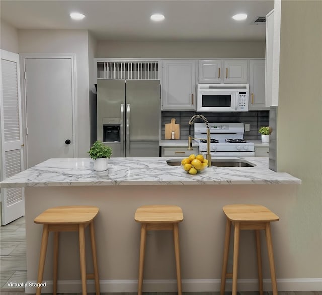 6916 Moccasin Dr, Plano, TX 75023 - kitchen with white appliances, white cabinets, light stone countertops, decorative backsplash, and recessed lighting