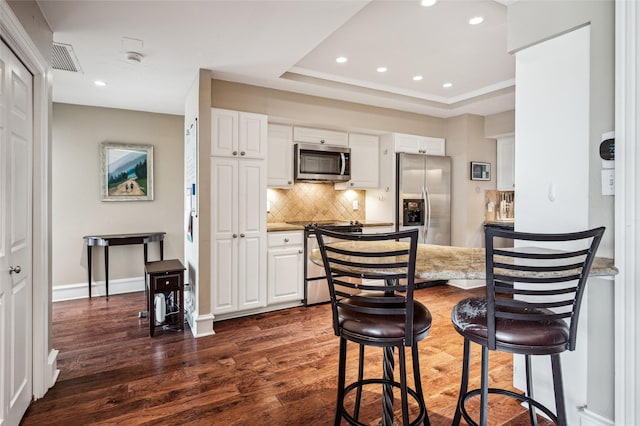 5200 Keller Springs Rd Unit 330, Dallas, TX 75248 - kitchen with appliances with stainless steel finishes, dark wood finished floors, decorative backsplash, recessed lighting, and white cabinets
