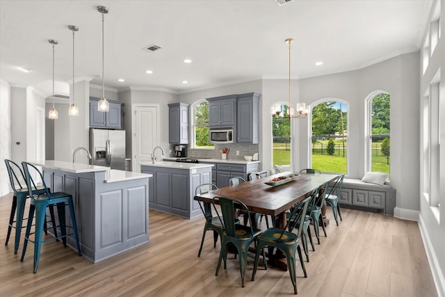 125 Oak Creek Dr, Tool, TX 75143 - kitchen with appliances with stainless steel finishes, a kitchen island with sink, gray cabinetry, tasteful backsplash, and light wood-style flooring