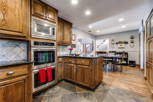 5301 Calumet Dr, Plano, TX 75023 - kitchen featuring appliances with stainless steel finishes, tasteful backsplash, a peninsula, recessed lighting, and brown cabinetry