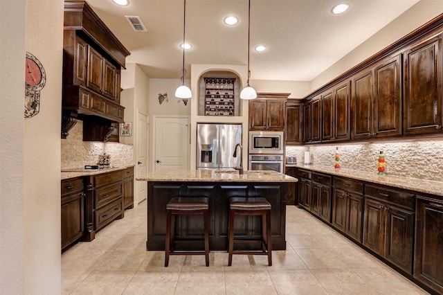 7205 E Nirvana Cir, North Richland Hills, TX 76182 - kitchen featuring stainless steel appliances, a sink, backsplash, an island with sink, and dark brown cabinetry