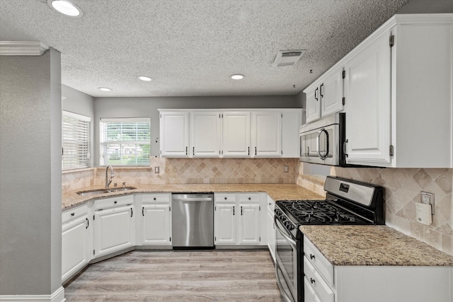 807 Fall Dr, Allen, TX 75002 - kitchen with stainless steel appliances, a sink, light wood finished floors, white cabinetry, and recessed lighting