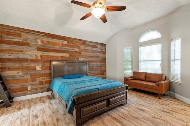 807 Fall Dr, Allen, TX 75002 - bedroom with lofted ceiling, light wood finished floors, wooden walls, a ceiling fan, and a textured ceiling