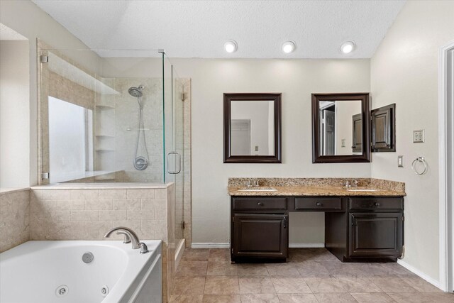 807 Fall Dr, Allen, TX 75002 - bathroom featuring a stall shower, a whirlpool tub, double vanity, baseboards, and a textured ceiling