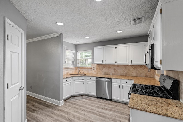 807 Fall Dr, Allen, TX 75002 - kitchen with stainless steel appliances, light wood-style floors, tasteful backsplash, a sink, and white cabinets