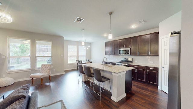 1916 Prestige Cove Ct, Wylie, TX 75098 - kitchen featuring stainless steel appliances, a sink, dark wood-style floors, dark brown cabinets, and a breakfast bar area