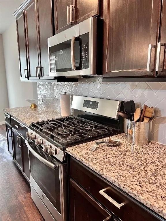 1916 Prestige Cove Ct, Wylie, TX 75098 - kitchen featuring appliances with stainless steel finishes, light stone counters, dark brown cabinetry, and dark wood-style flooring
