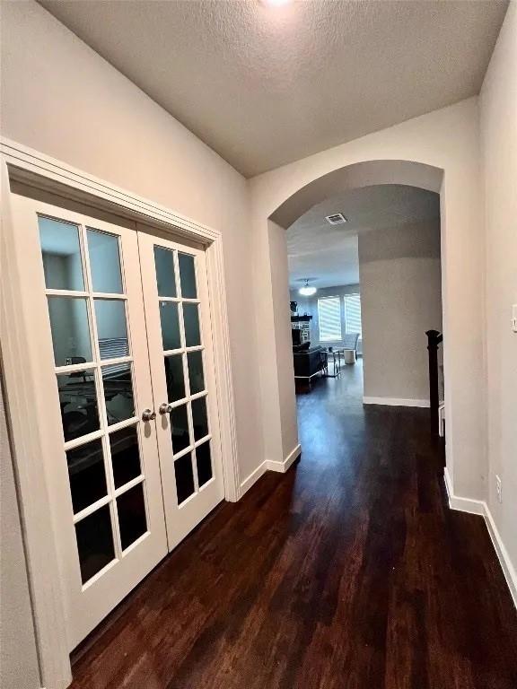 1916 Prestige Cove Ct, Wylie, TX 75098 - hall with arched walkways, wood finished floors, french doors, baseboards, and a textured ceiling