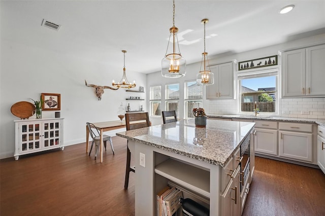 5224 Sonata Trl, Fort Worth, TX 76126 - kitchen featuring a chandelier, open shelves, tasteful backsplash, dark wood-type flooring, and light stone countertops