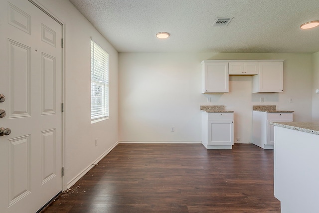 1423 Queen Annes Dr, Burleson, TX 76028 - kitchen featuring a textured ceiling, dark wood-style flooring, white cabinets, baseboards, and light stone countertops
